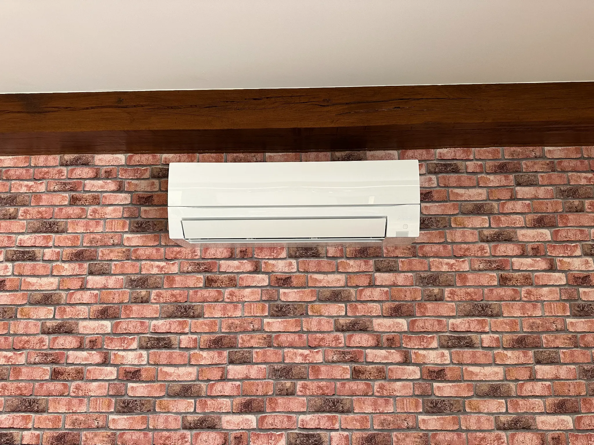 Climatisation Mitsubishi Electric air conditioning systems sur un mur en pierre rouge
